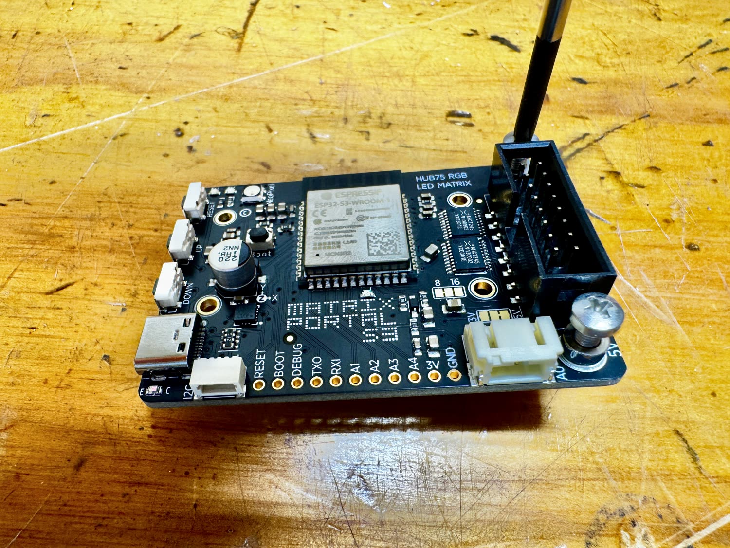 The keyed black HUB75 connector being pressed onto the MatrixPortal S3 pins
